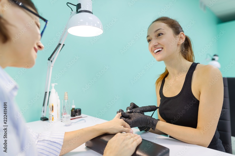 Woman in nail salon receiving manicure by manicurist, closeup manicure process. Nail and hand care in beauty salon. Woman in nail salon receiving manicure by manicurist, closeup manicure process. Nail and hand care in beauty salon.