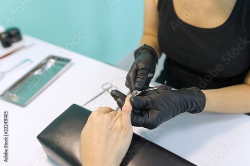 Close-up process of professional manicure  hands of manicurist and female client  instruments