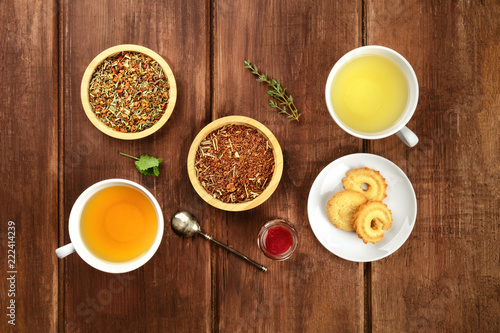 Tea tasting. Various cups of tea and leaves of loose tea with biscuits and jam