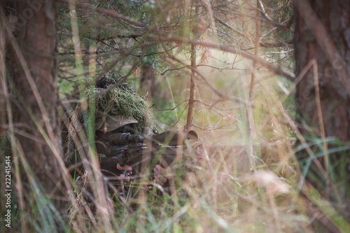 Sniper wearing ghillie camouflage in action