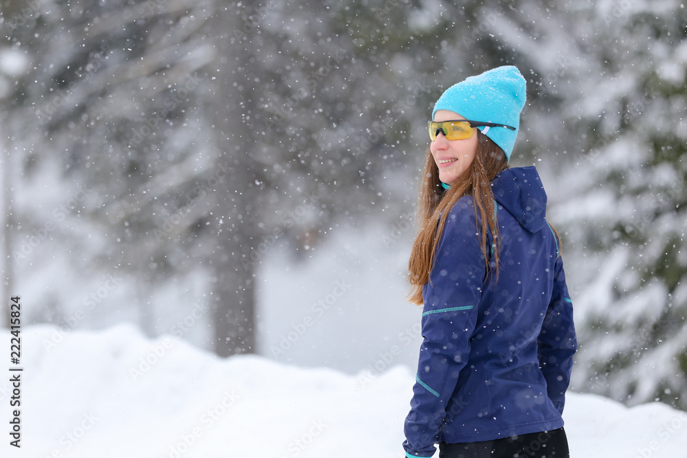 Young runner woman standing at the road in winter. Smiling girl resting after morning jog training enjoying winter weather Young runner woman standing at the road in winter. Smiling girl resting after morning jog training enjoying winter weather