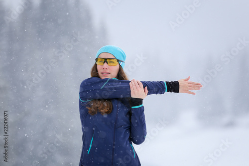 Young woman stretching before road running in winter. Sporty girl warming up before jogging