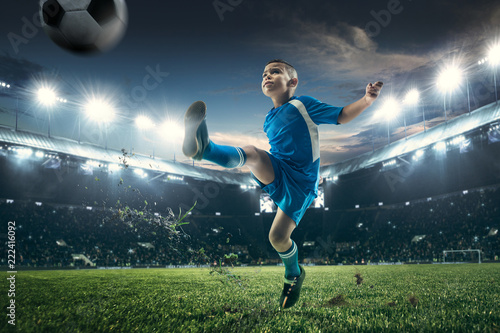 Young boy with soccer ball doing flying kick at stadium. football soccer players in motion on green grass background. Fit jumping boy in action, jump, movement at game. Collage