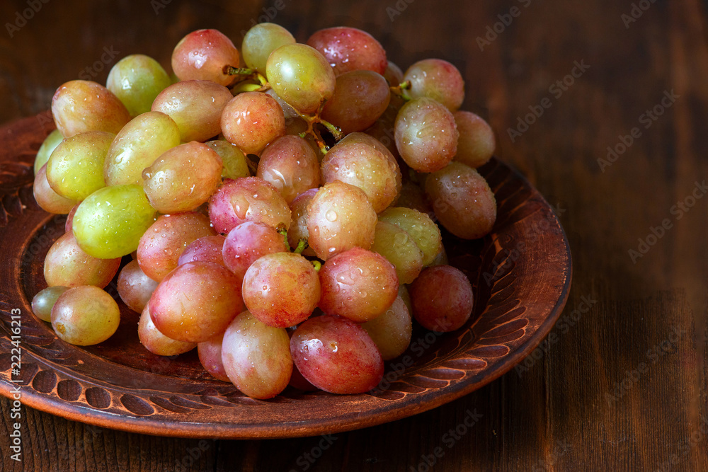 grape on brown plate on dark wooden background