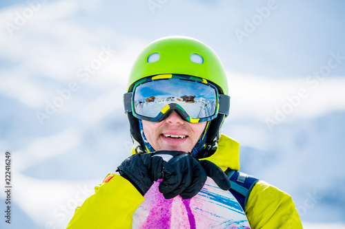 Photo of sportive man with snowboard against background of mountains