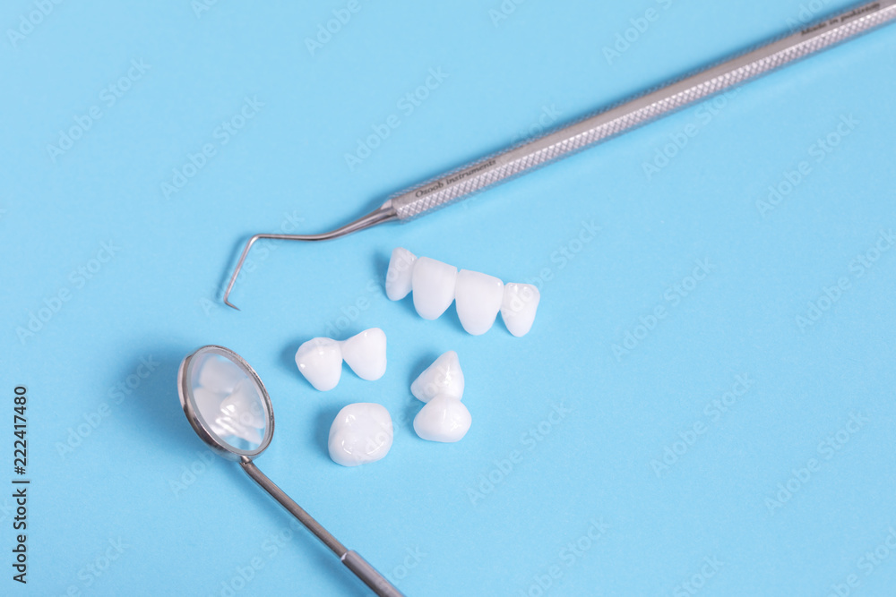 Dental tools and zircon dentures on a blue sheet - Ceramic veneers - lumineers Dental tools and zircon dentures on a blue sheet - Ceramic veneers - lumineers