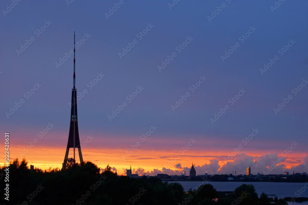 Fototapeta premium Summer sundown after storm in Riga, television tower on the front and trees and city buildings on the background on the horizon