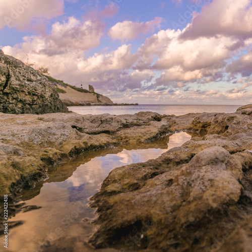 Sunset reflected on puddle of sea water in Porto Torres