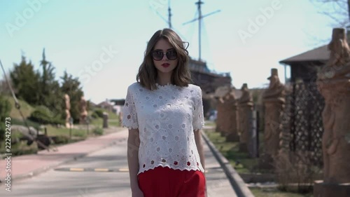 Charming young woman with a magnificent golden hair, gorgeous red lipstick and stylish look. Attractive young lady removes sunglasses while walking in european street.