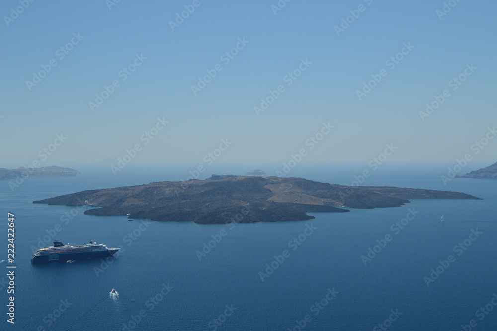 Views of the Thera Bay from Fira with a moored cruise on it and the beautiful view of the island that sits opposite. Architecture, landscapes, travel, cruises. July 7, 2018.  Santorini, Thera. Greece.