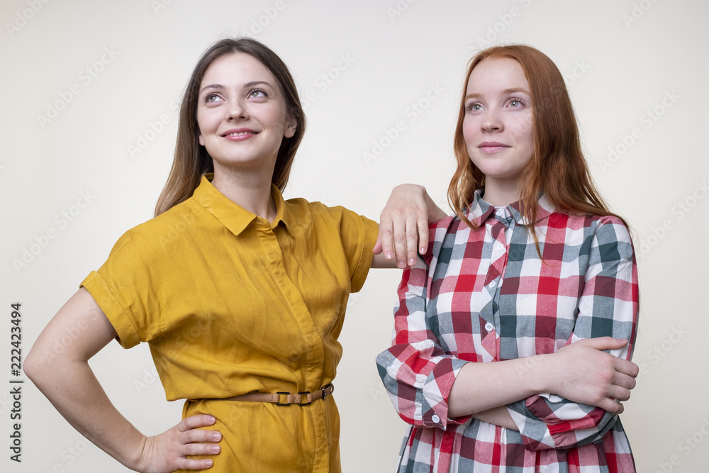 Two content beautiful young female friends looking away Two content beautiful young female friends looking away