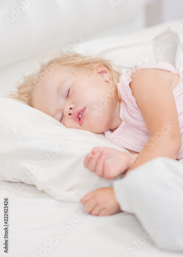 little blonde baby girl sleeping on a bed
