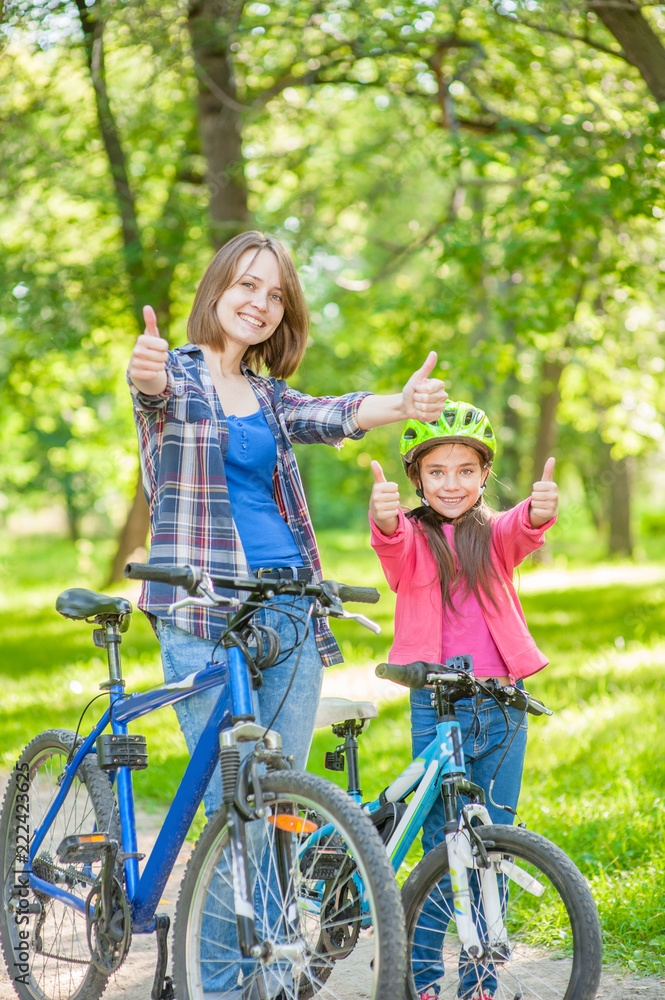 Naklejka premium happy mom with her daughter on bicycles show thumbs up