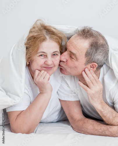Senior man kissing his wife under the blanket