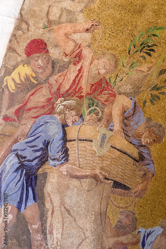 Vertical detail of colorful mosaic on the exterior of St. Mark's Basilica depicting the transportation of St. Mark's body to Venice, Italy.