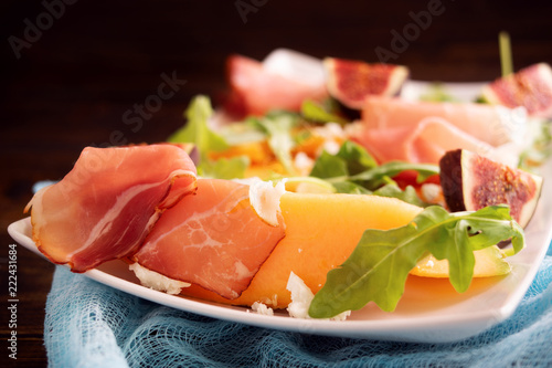 Close up of plate with melon, arugula and prosciutto