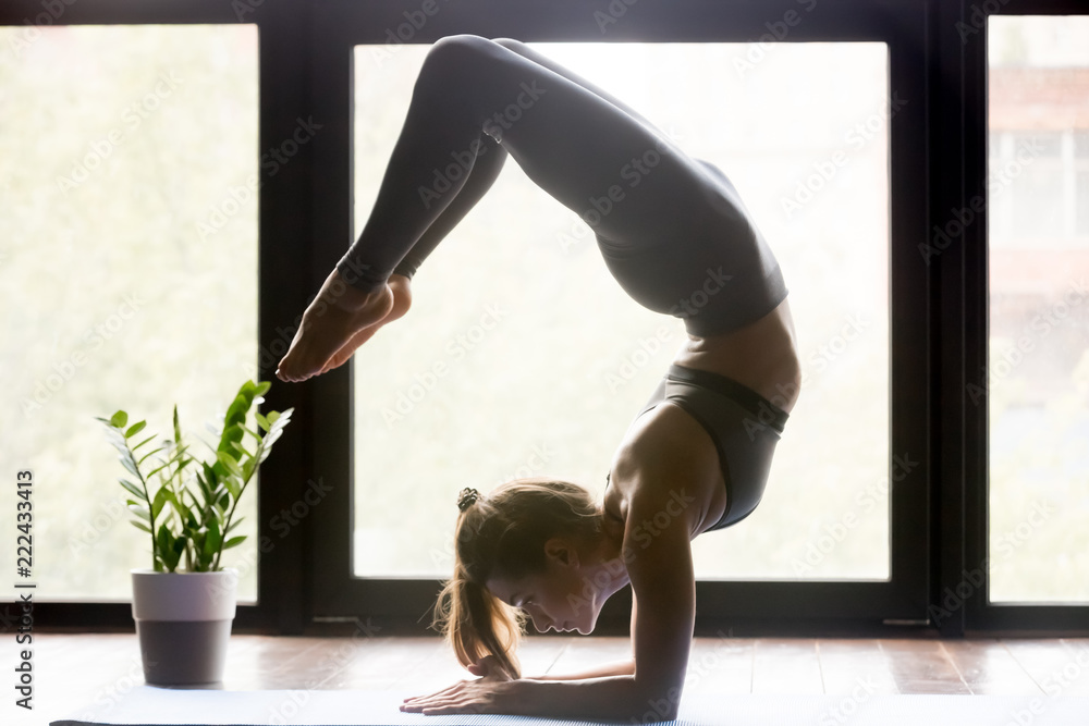 Young sporty woman practicing yoga, doing Scorpion backbend exercise,  Vrischikasana pose, working out wearing sportswear grey pants and top,  indoor full length, yoga studio Stock Photo | Adobe Stock