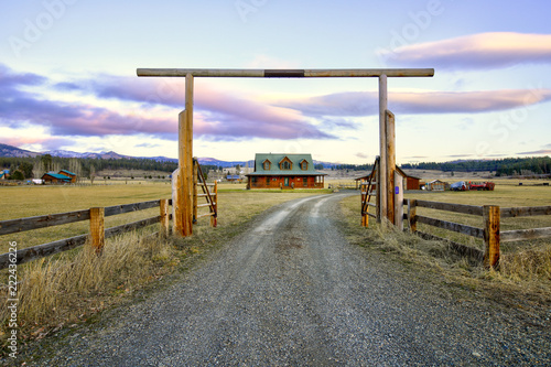 Entry gate to a nice wooden ranch home with beautiful landscape. photo