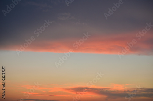 Cloudscape in dusk with clouds in grey, violet and orange colors and blue sky - suitable for a background © branislav