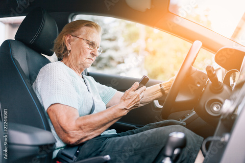 Εκτύπωση καμβά Elderly woman behind the steering wheel using her phone