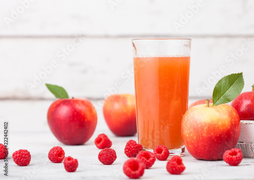 Glass of fresh organic apple and raspberry juice with fresh fruits in box on wooden background