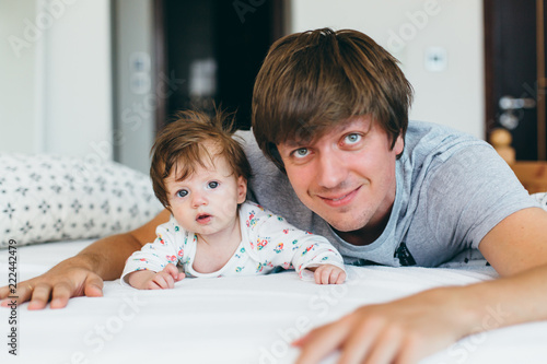 Portrait of little baby girl and her father on a bed