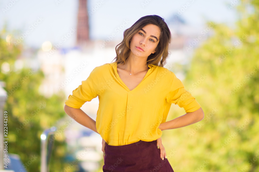 Portrait of a young woman in bright yellow blouse with hands on her hips Portrait of a young woman in bright yellow blouse with hands on her hips
