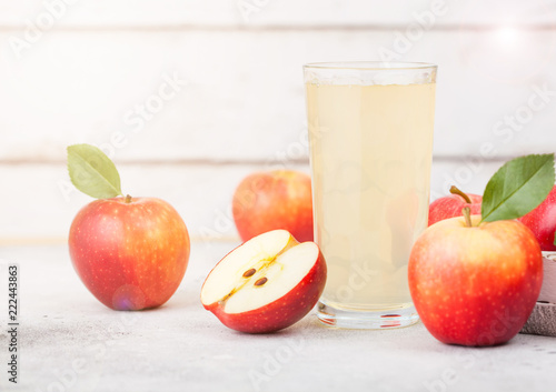 Glass of fresh organic apple juice with braeburn pink lady apples in box on wooden background with sun light