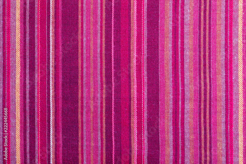 Striped fabric texture with multiple warm colors (purple, purple, magenta, pink, red, maroon, orange, yellow). Close-up of the tissue. Ethnic aspect