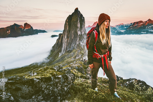 Woman with backpack hiking in sunset  mountains adventure outdoor in Norway active vacations traveling lifestyle Segla peak