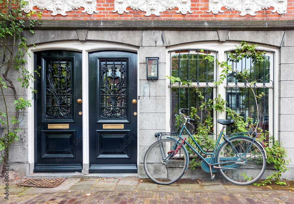 Fototapeta premium Typical house entrance with two doors, window, and bicycle in the old town of Amsterdam, Netherlands