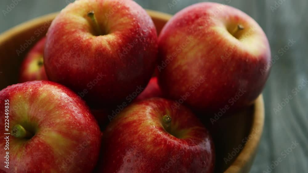 Closeup shot of bowl filled with plenty whole red apples with shiny skins in daylight Closeup shot of bowl filled with plenty whole red apples with shiny skins in daylight