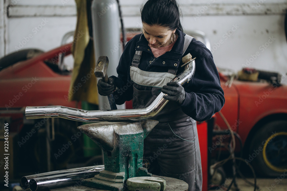 Strong and worthy woman doing hard job in car and motorcycle repair shop.
