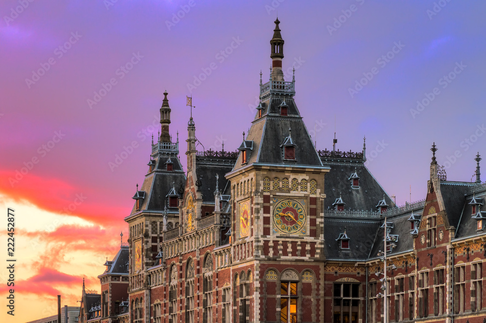 Fototapeta premium Piękny widok na zabytkowy dworzec kolejowy Amsterdam Central, o zachodzie słońca