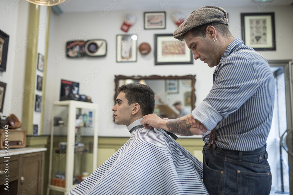 Barbero moderno con vestimenta vintage corta el pelo a joven muchacho ...