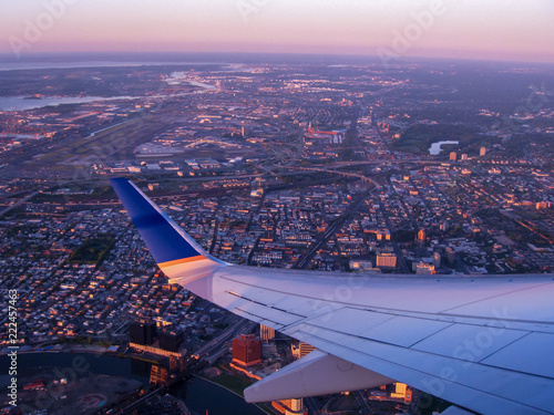 Flying over a city coming in to land at the airport and looking out the window at the beautiful evening colors.