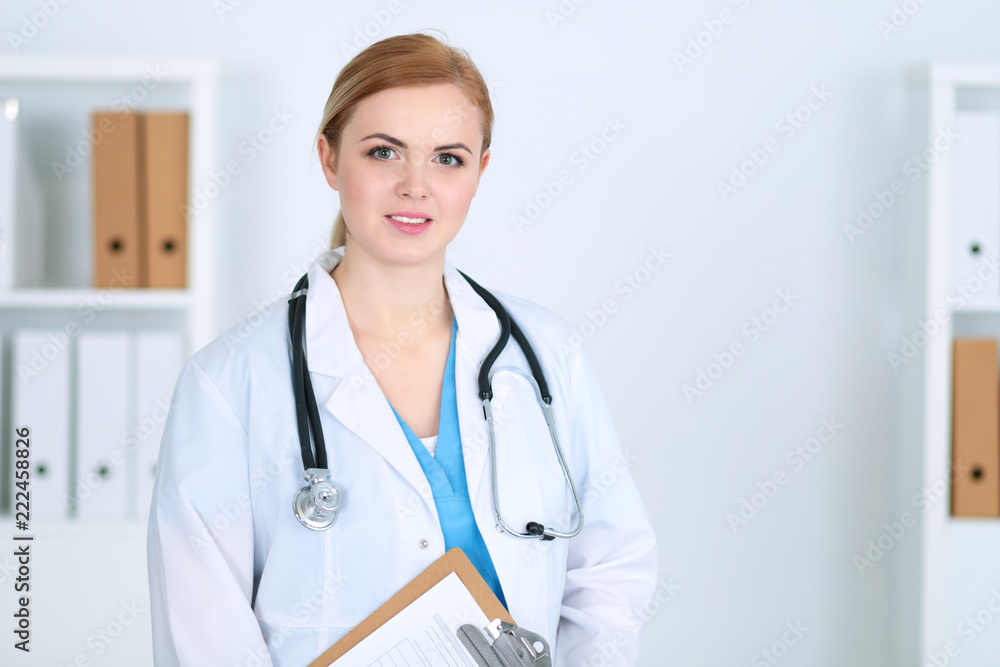 Beautiful female medical doctor standing at hospital. Physician is ready to help patients. Medicine and health care concept Beautiful female medical doctor standing at hospital. Physician is ready to help patients. Medicine and health care concept