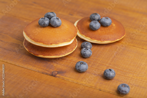 A stack of American pancakes or pancakes with blueberries and mint on a wooden table. Delicious dessert for Breakfast.