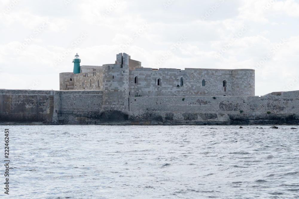 The gorgeous seafront of the island of Ortigia, in the city of Siracuse, Sicily(Italy). In this shot taken from a boat you can see the old city walls and the Maniace castle built in the 13th century.