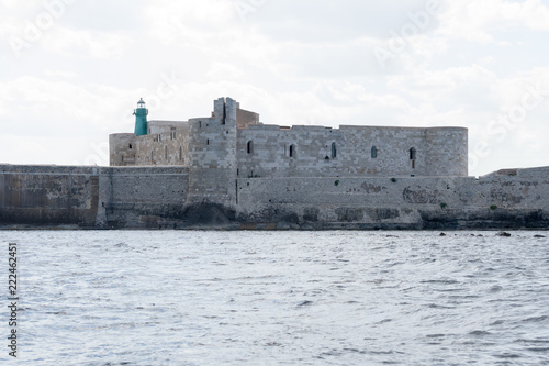 The gorgeous seafront of the island of Ortigia, in the city of Siracuse, Sicily(Italy). In this shot taken from a boat you can see the old city walls and the Maniace castle built in the 13th century. photo