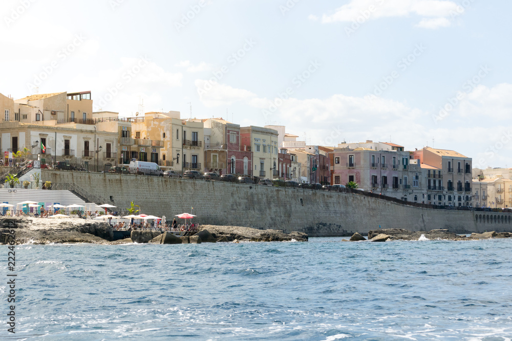 The gorgeous seafront of the island of Ortigia, in the city of Syracuse, Sicily(Italy). In this shot you can see the old city walls, the typical local houses and baroque-style church facing the sea