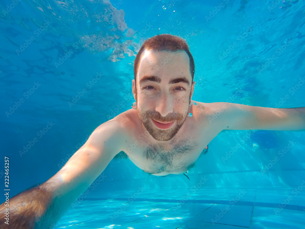 Young handsome man diving underwater in a swimming pool