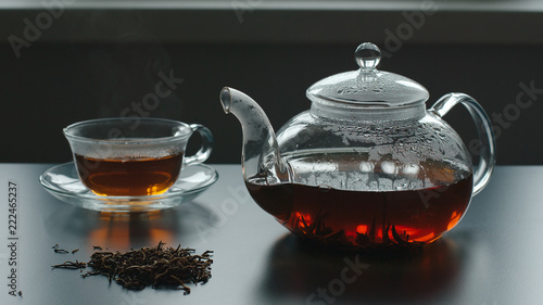 Teapot, tea crop and glass cup are near