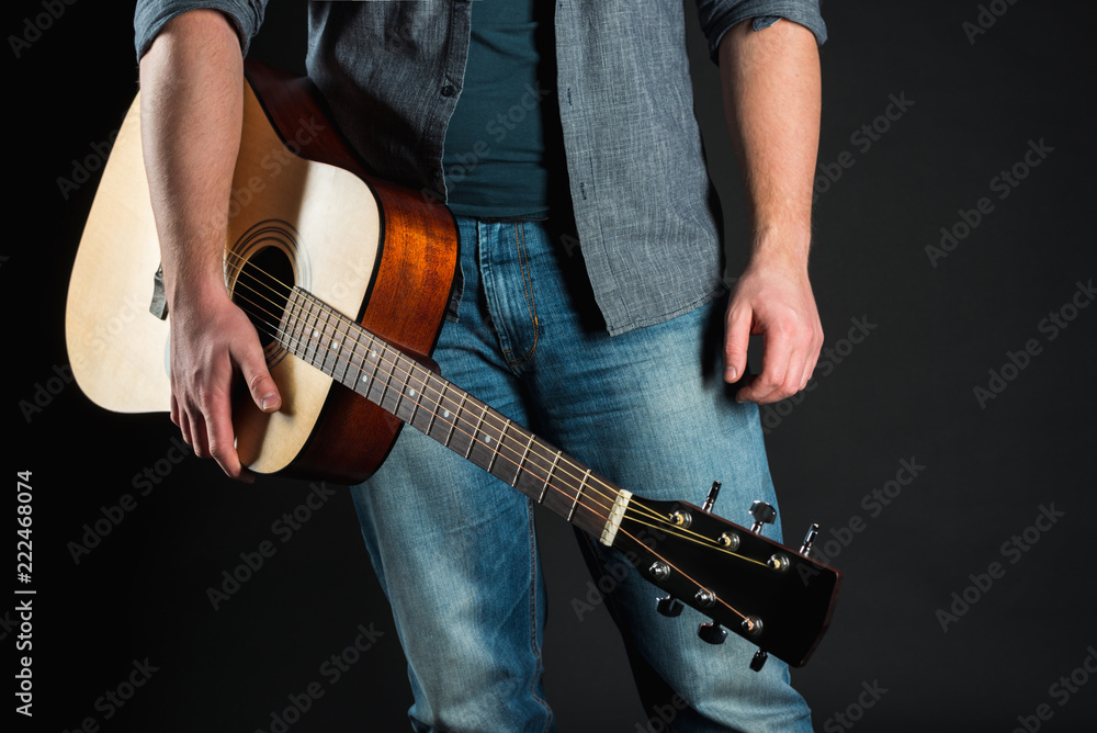 Men's hands hold an acoustic guitar