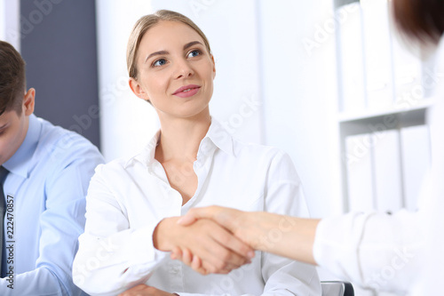 Business handshake by blonde woman and her partner at meeting. Concept of success and agreement
