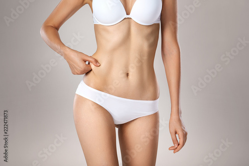 Unrecognizable woman in underwear testing fat layer on waist