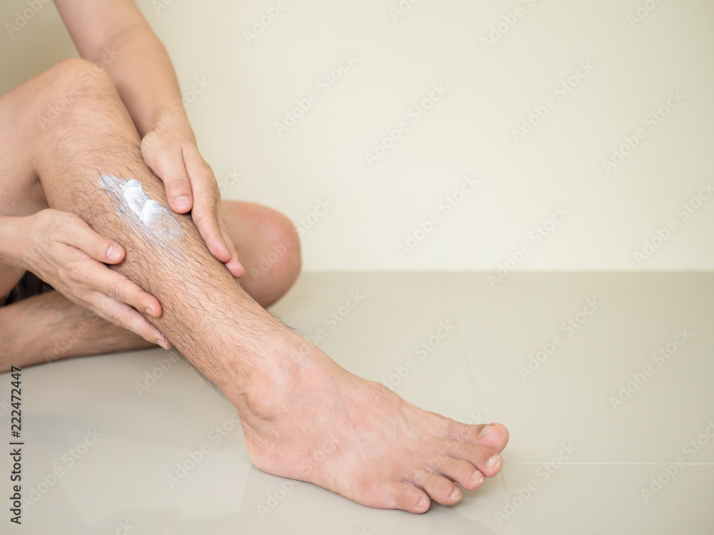 Fototapeta premium Men apply lotion to the skin leg.