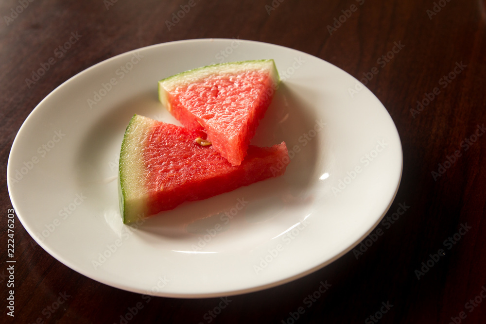 Slice of delicious watermelon on white plate background