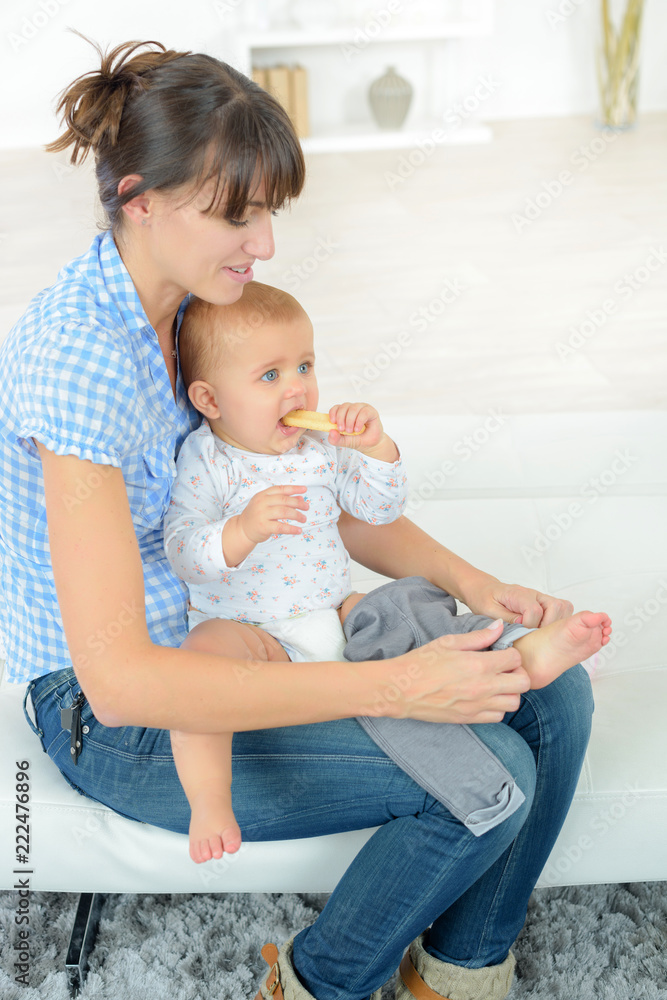 mother dressing her baby on a couch mother dressing her baby on a couch