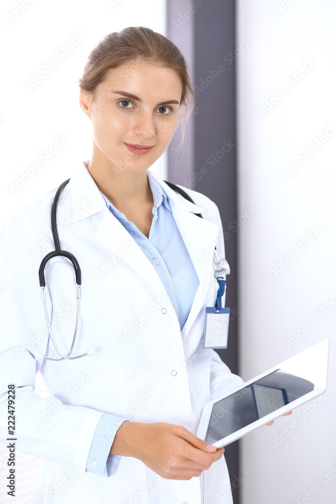 Doctor woman in clinic office. Female physician at work using digital tablet while standing straight at hospital. Medicine and healthcare concept Doctor woman in clinic office. Female physician at work using digital tablet while standing straight at hospital. Medicine and healthcare concept